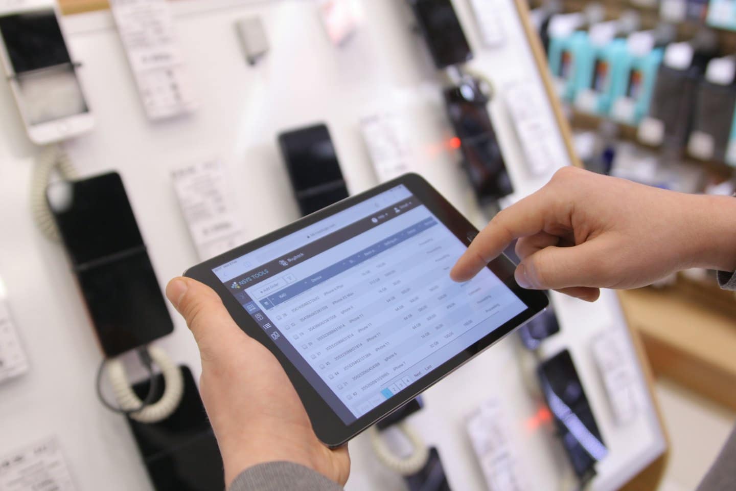 Mani che gestiscono l'inventario del negozio su uno schermo di tablet.